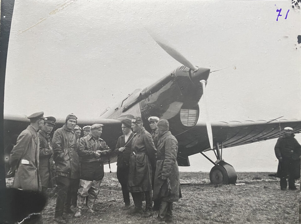 Групповой снимок среди летчиков и пограничников в центре стоит в летном костюме В. П. Чкалов. На заднем плане самолет АНТ-25. Остров Удд, после перелета, 1936 г.